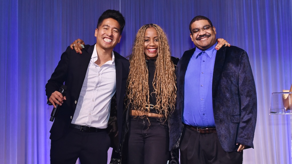 Three speakers on stage face camera at 12th annual Leaders of Change